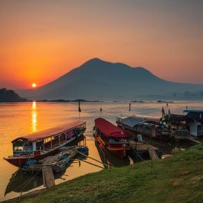 Mekong River sunrise with skiffs and ferry boat