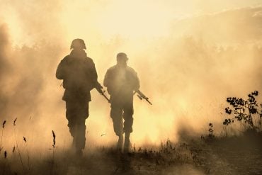 Soldiers walking through smoky field
